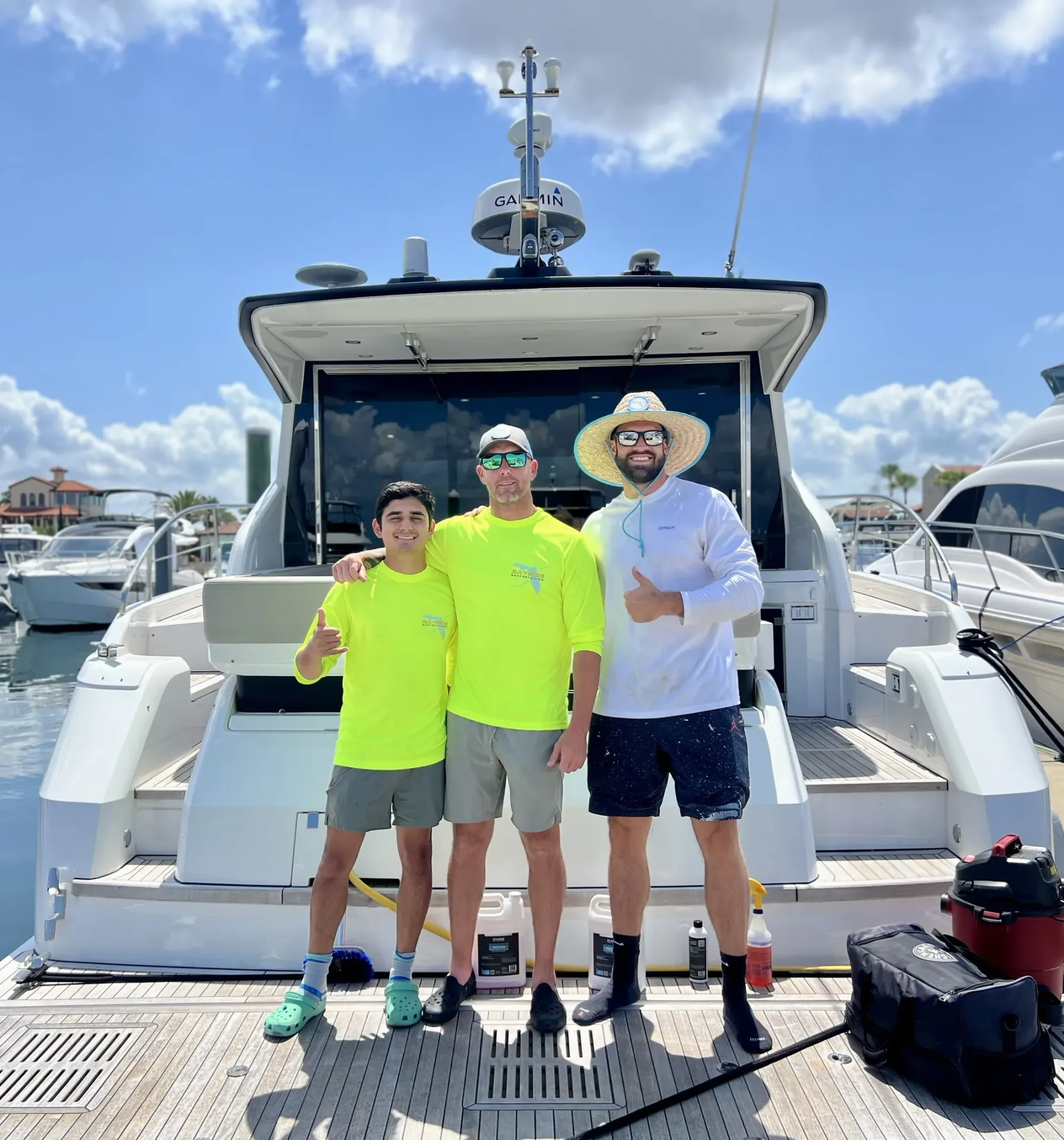 Three of the Bayside crew on the deck of a boat they have just finished, in the sun at a Tampa Bay marina.